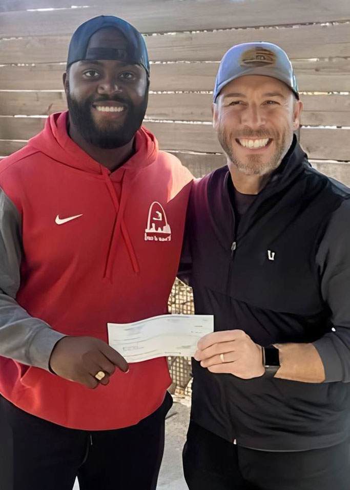 cw4k board member Jason Roeslein presents donation check to Estevenson Coleman Program Manager at Brace for Impact 46 in support of clean water efforts at CHIDA Hospital in Haiti X